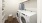 Walk-in laundry room featuring full-size washer and dryer, built-in shelves for organization, and a hanging rack for drying clothes.
