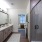 Primary bathroom featuring a sleek stand-up shower, large sink with ample counter space, framed mirror, and bright, stylish lighting.